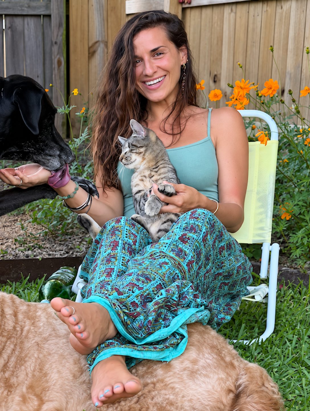 Brittany smiling in a garden with dogs and a kitten